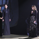 Clare Waight Keller is watched by Meghan, Duchess of Sussex and Rosamund Pike as she speaks on stage after receiving the award for British Designer of the Year Womenswear Award for Givenchy.